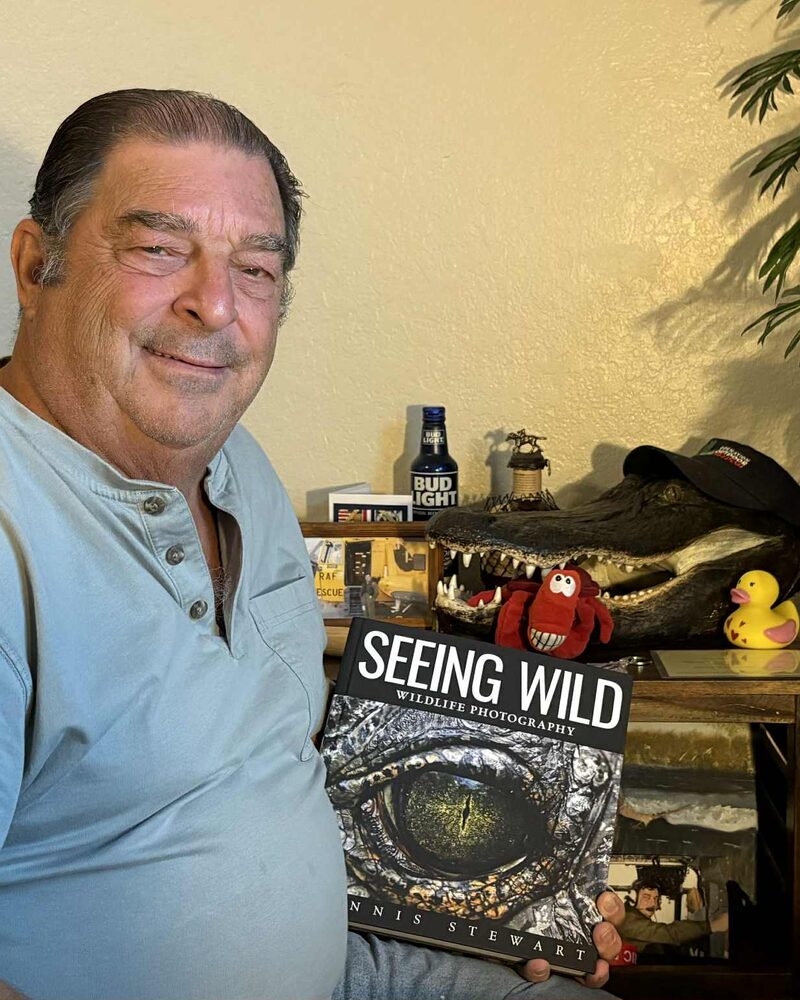 Reader holding Seeing Wild beside an alligator display