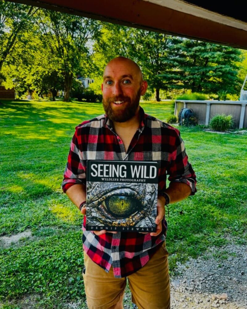Reader holding Seeing Wild outdoors